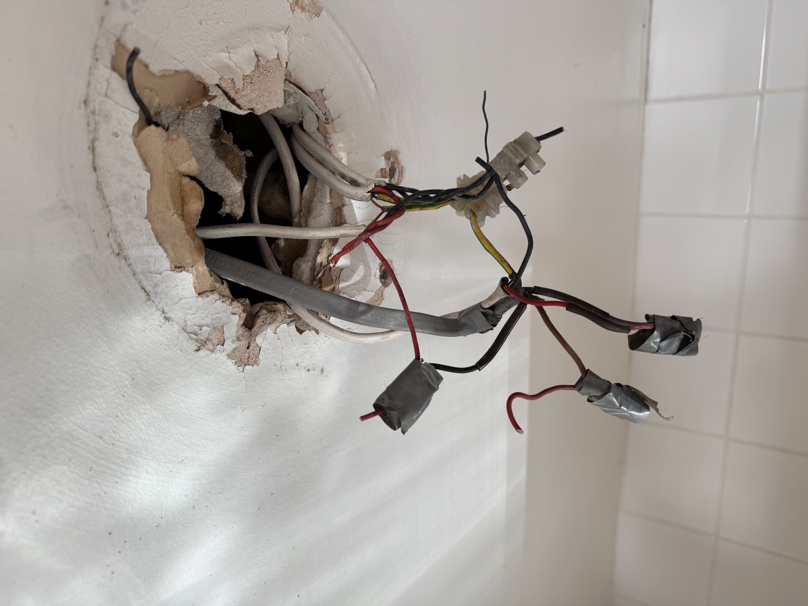 The tangled nest of taped-up cable joints we found hidden behind the old bathroom light in Caversham